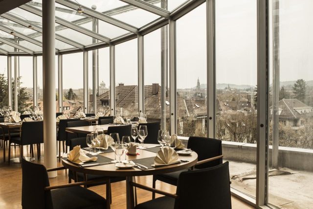 красивый вид на достопримечательности Берна через панорамное окно ресторана отеля